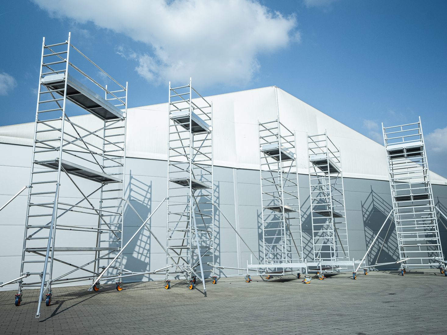 AL-TO PRO+ scaffold towers of different heights in front of a hall